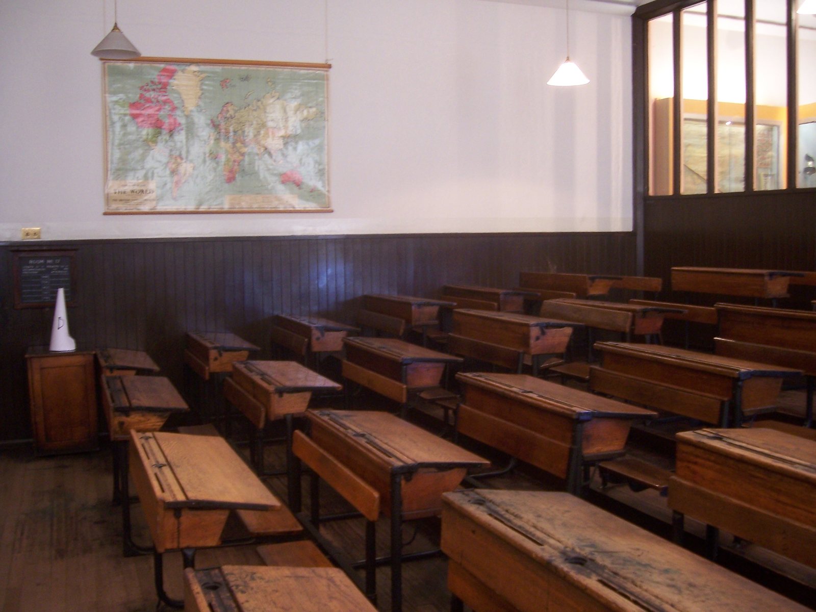 Leeg klaslokaal met houten schoolbanken en een wereldkaart aan de muur